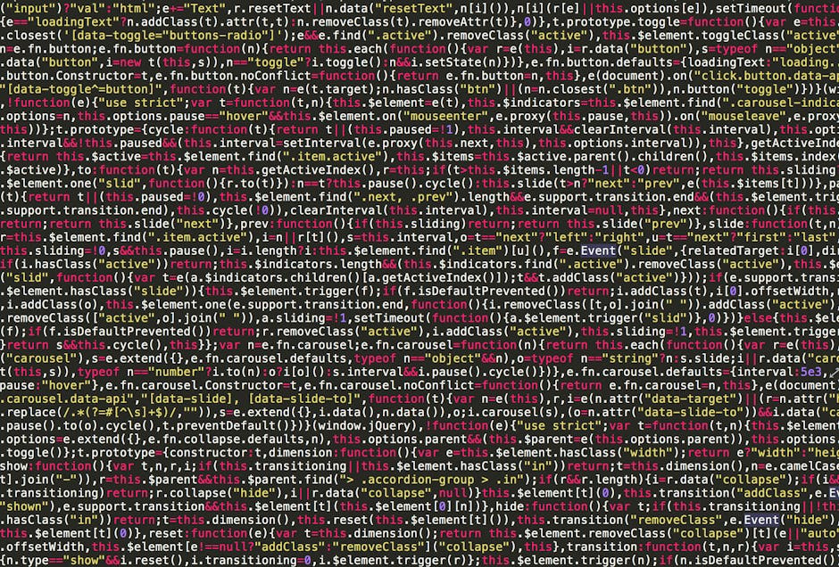 A close-up view of a person's hand using a laptop on a wooden desk, with the screen displaying lines of code in a text editor. The individual is wearing a wristwatch, and the background is blurred, fo